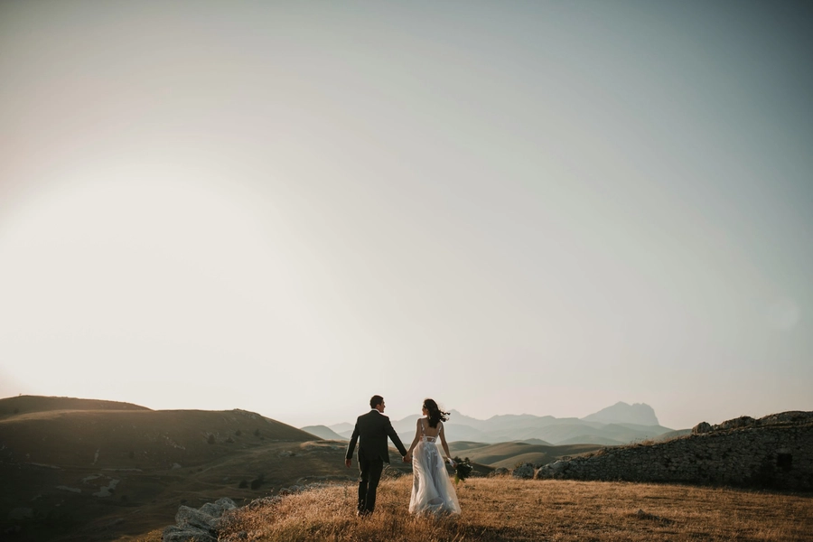 bride and groom holding hands on hill